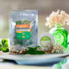 Close-up view of Appalachian Standard's Full Spectrum CBD & THC gummies package and Sweet Clover CBD Body Cream jar displayed on a white plate, surrounded by delicate white flowers, green leaves, and soft green accents creating an elegant product presentation